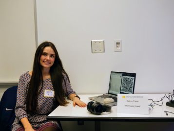Sydney Fraser sitting by a laptop and headphones with her project, "The Passion Project."